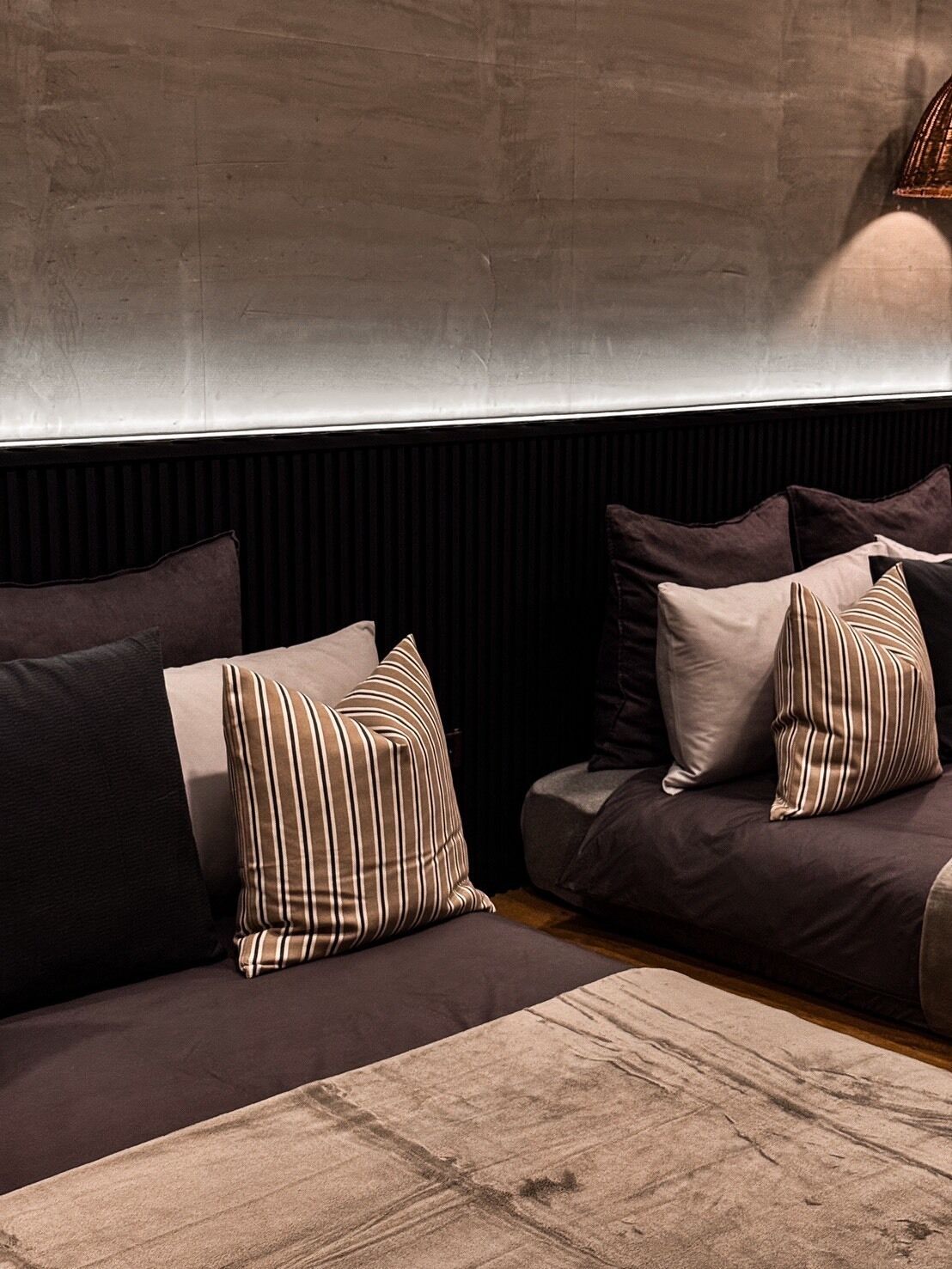A modern living room with a dark-colored sofa and multiple pillows.
