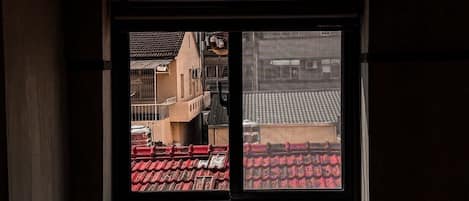 Una ventana con vistas a un edificio de tejados rojos y un balcón.
