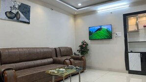 Una sala de estar moderna con un sofá de cuero marrón, una mesa de centro de vidrio, un televisor de pantalla plana y un cuadro en la pared.