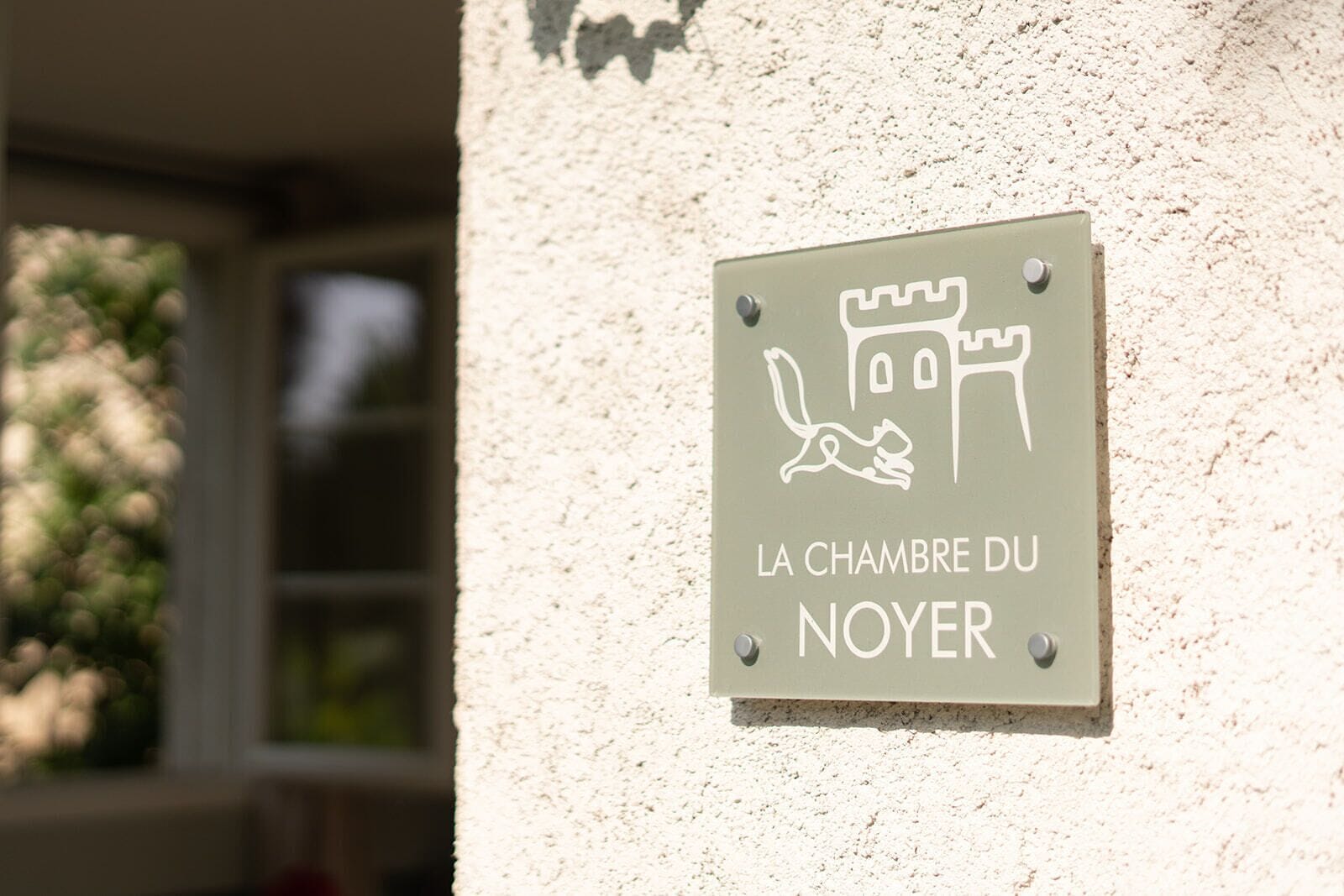 Et skilt med illustration af et slot og en kanin, mærket "LA CHAMBRE DU NOYER".