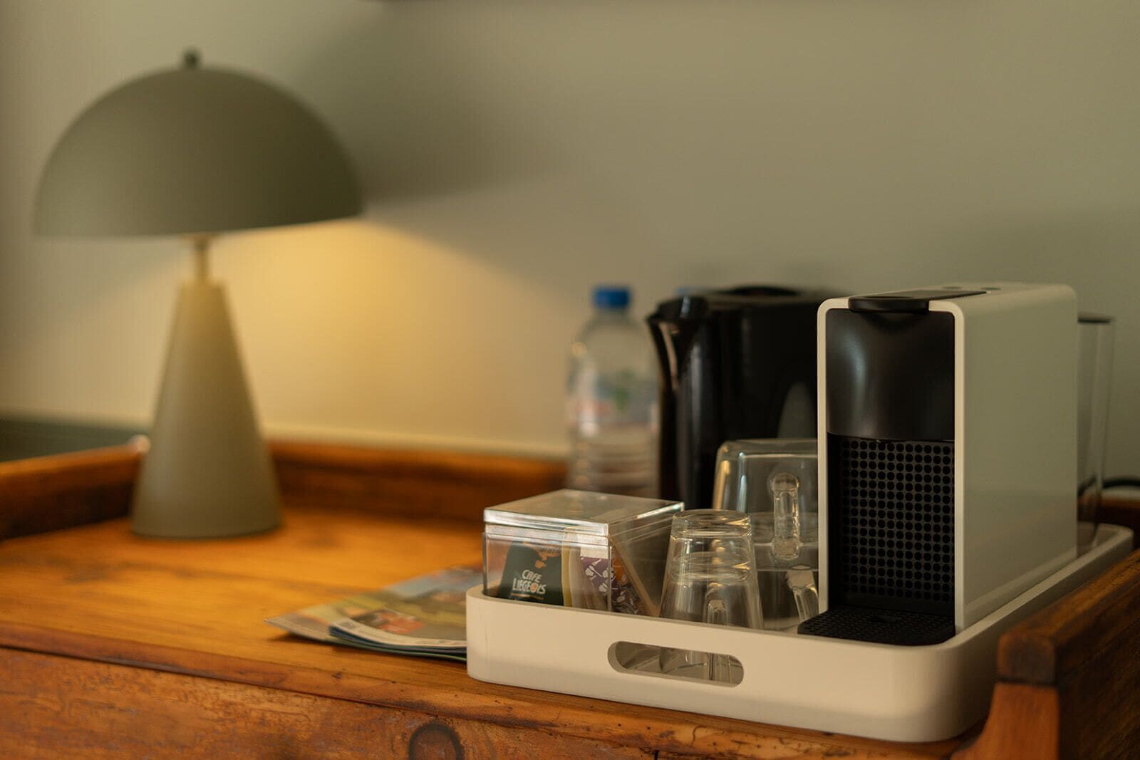 Een kleine keukenindeling met een koffiezetapparaat, een waterkoker en een glazen pot op een houten tafel.