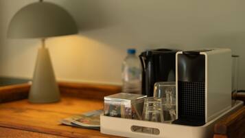 Een kleine keukenindeling met een koffiezetapparaat, een waterkoker en een glazen pot op een houten tafel.