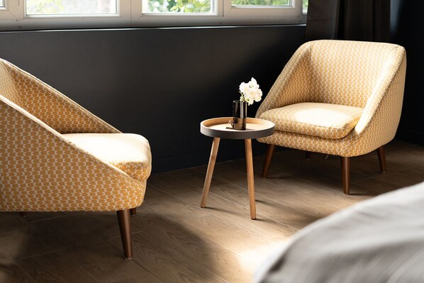 A room with two patterned armchairs and a small round table with a vase of flowers. - Le Clos du Château (Amboise)