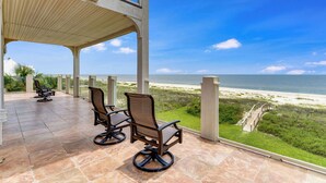 An outdoor patio with two chairs and a view of the beach.