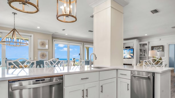 A modern kitchen with white cabinetry, stainless steel appliances, and a large island.