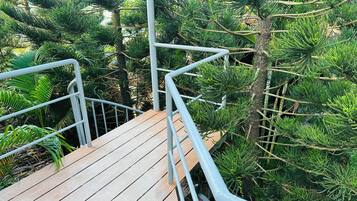 Eine Holztreppe mit Metallgeländern, umgeben von dichtem Grün.