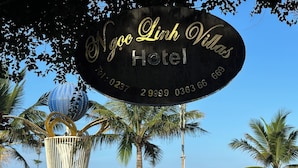 A sign for Ngoc Linh Villas Hotel with contact numbers. - Ngoc Linh Villas Hotel (Hải Hòa)