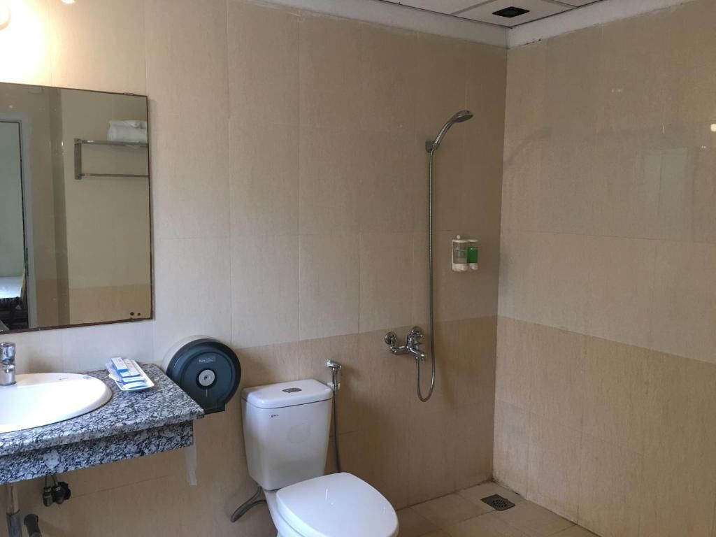 Et badeværelse med vask, toilet og bruser.