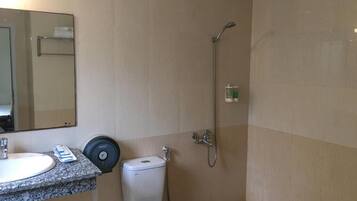 Et badeværelse med vask, toilet og bruser.