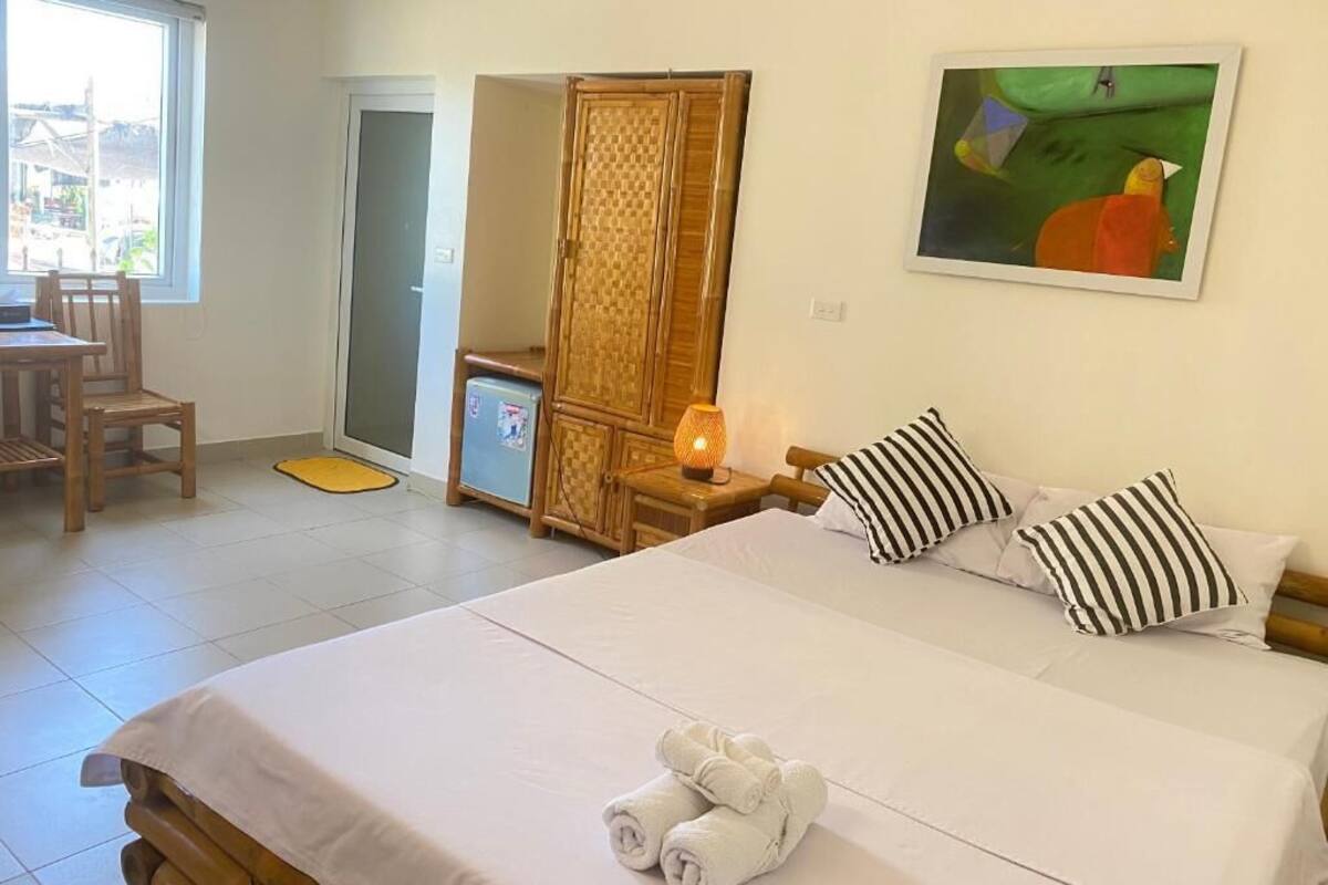 Ett hotellrum med en säng, ett skrivbord, en stol, en garderob och en tavla på väggen.