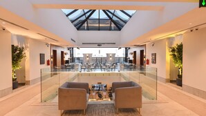 A spacious lobby with a high ceiling, glass railings, and a central seating area with two sofas. - Marsal Park Hotel (Riyadh)