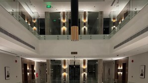 A modern hotel lobby with a glass atrium, multiple floors, and a central elevator area. - Marsal Park Hotel (Riyadh)