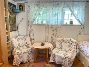 Una camera accogliente con un letto, due poltrone, un tavolino e una finestra con tende.
