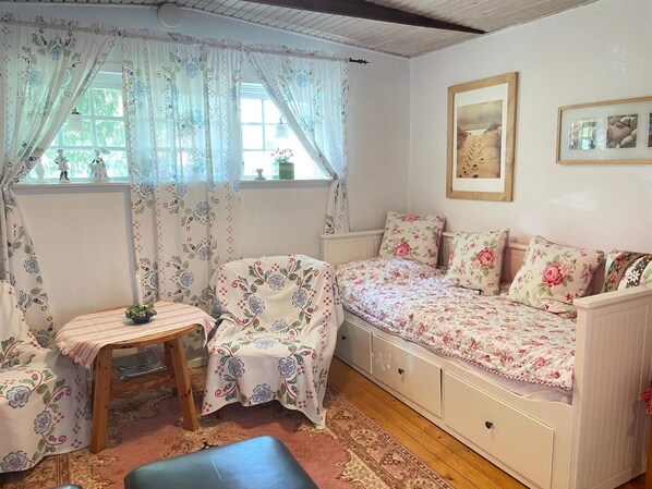 A cozy room with a bed, a small table, and a window with curtains.