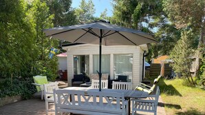 Un espace patio avec une table et des chaises, un coin salon abrité et une vue sur une maison en arrière-plan.