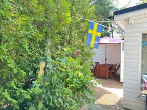 Un jardin avec un drapeau suédois, une table en bois et des chaises.