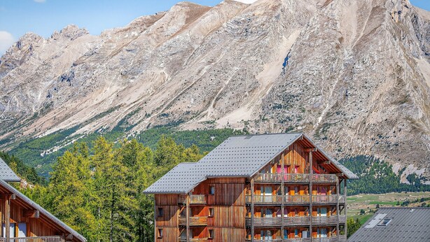 A wooden chalet with balconies, set against a mountainous backdrop. - Studio "Le 27" with Mountain View, Balcony & Wi-Fi – Sleeps 4, 2 Extra for an Additional Fee (Dévoluy)