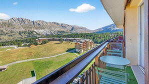 A balcony with a view of mountains, a grassy area, and a building complex. - Studio "Le 27" with Mountain View, Balcony & Wi-Fi – Sleeps 4, 2 Extra for an Additional Fee (Dévoluy)