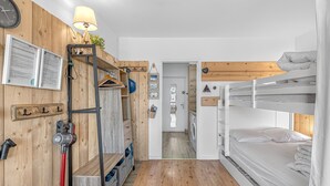 A bunk bed room with a wooden wall, a lamp, a clock, and a laundry area. - Studio "Le 27" with Mountain View, Balcony & Wi-Fi – Sleeps 4, 2 Extra for an Additional Fee (Dévoluy)