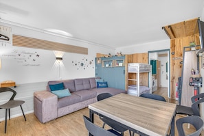 Un espacio habitable compacto con sofá, mesa de comedor y kitchenette.