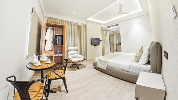Une chambre d’hôtel moderne équipée d’un lit, d’un bureau avec une chaise, d’une armoire et d’un téléviseur.