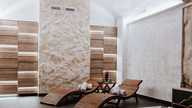 Un espace de détente avec un jacuzzi, des chaises longues en bois et un mur en pierre.