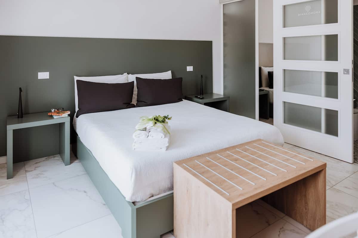 A neatly arranged bedroom with a bed, bedside tables, and a wooden bench.