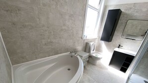 Un bagno moderno con una vasca da bagno ampia, un water e un lavandino.