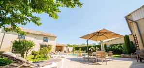 Una casa amb piscina, mobles de jardí i una pèrgola.
