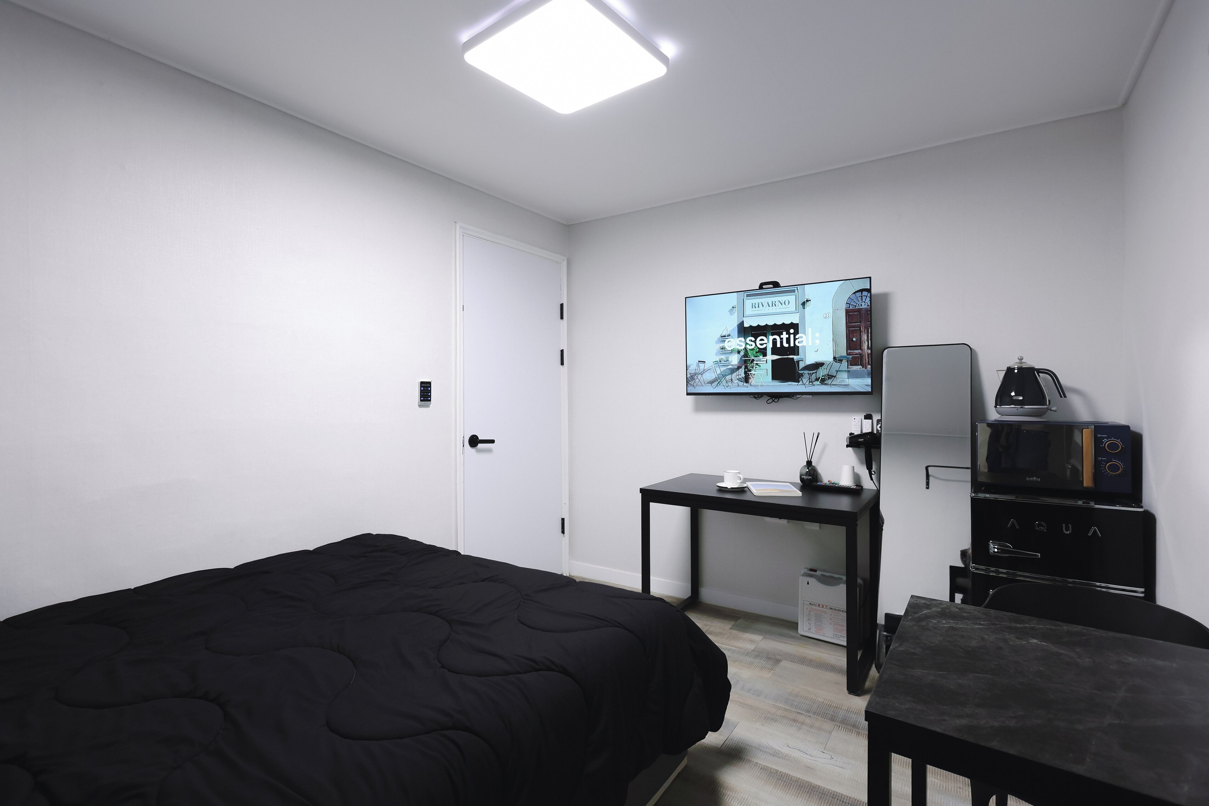 Una habitación de hotel con cama, escritorio con cafetera, televisión y minibar.