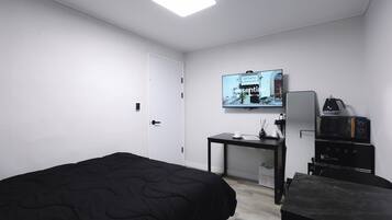 Una habitación de hotel con cama, escritorio con cafetera, televisión y minibar.