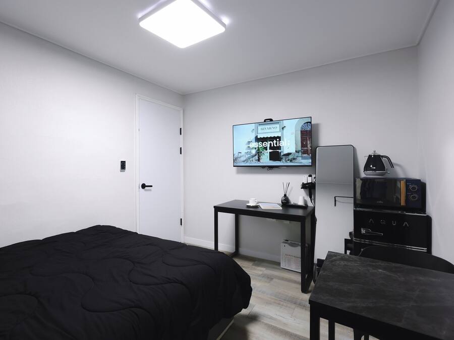 Una habitación de hotel con cama, escritorio con cafetera, televisión y minibar.