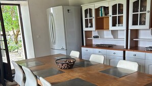 Ein Essbereich mit Holztisch, weißen Stühlen, einer Nuss-Schale und einem weißen Kühlschrank.