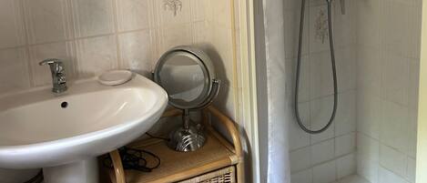 A bathroom with a sink, mirror, and shower.