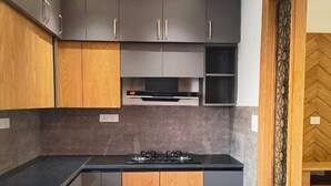Une cuisine moderne avec des meubles de couleur sombre, un plan de travail noir et une cuisinière intégrée.
