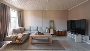 Ein modernes Wohnzimmer mit Sofa, Couchtisch und Fernseher.
