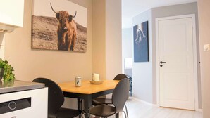 A dining area with a table, chairs, a refrigerator, and a wall-mounted picture of a bull. - Practical 3-Beds Apartment in Tromsø (Tromsø)