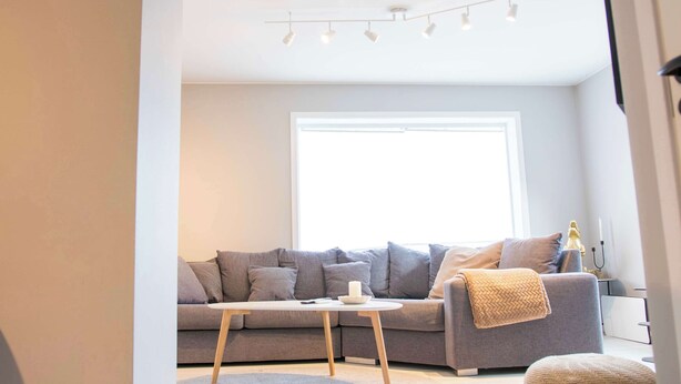 A modern living room with a grey sofa, a small white coffee table, and a large window providing natural light. - Practical 3-Beds Apartment in Tromsø (Tromsø)
