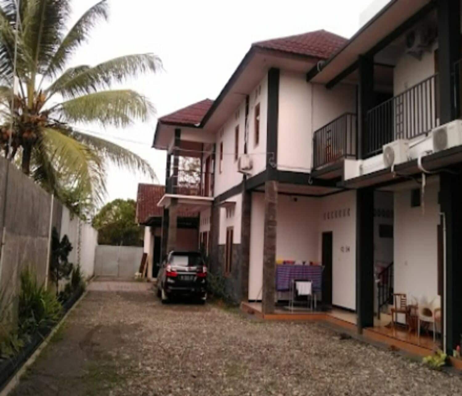A two-story house with a car parked in the driveway, a balcony, and a covered porch area.