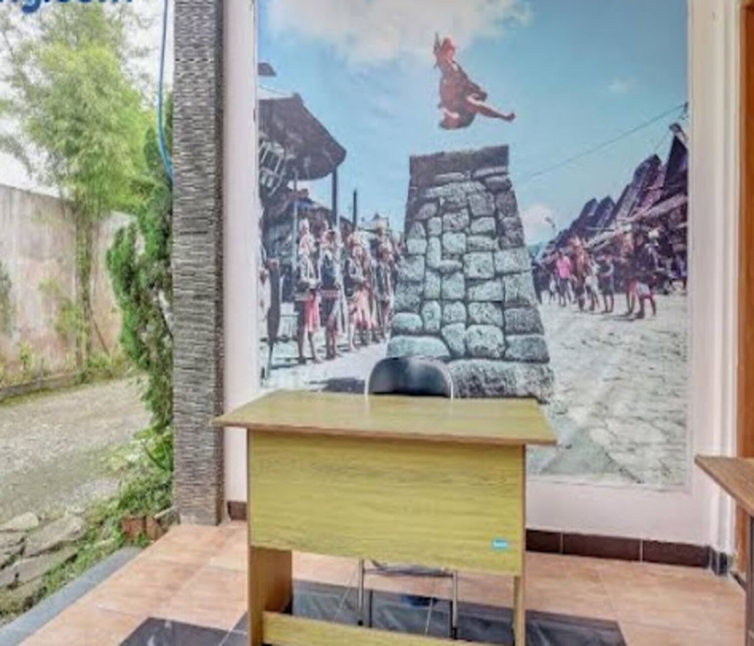 A room with a desk, a mural depicting a historical scene, a stone wall, and a view of a garden.