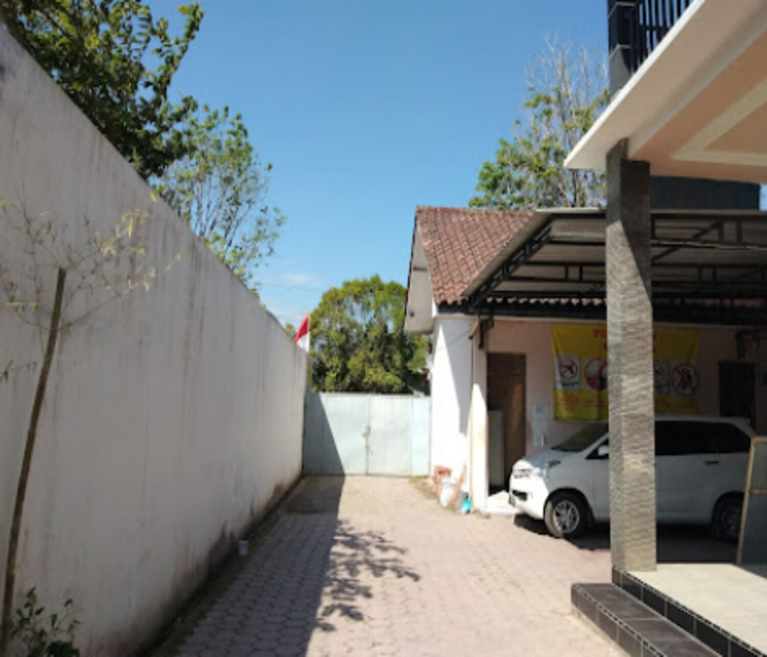 A paved driveway leading to a building with a tiled roof and a parked car.