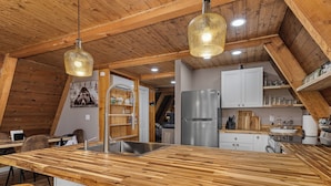 A kitchen with a wooden island, stainless steel appliances, and pendant lighting. - Secluded Cabin with Hot Tub, Firepit (Murray)