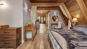 A bedroom with a wooden ceiling, a bed with a patterned bedspread, a desk with a chair, and a dresser. - Secluded Cabin with Hot Tub, Firepit (Murray)