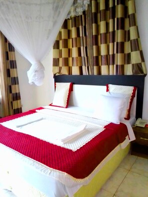 A neatly made bed with a red and white bedspread, white pillows, and a canopy.