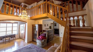 Un salon spacieux avec un escalier en bois, un lustre et une cheminée.