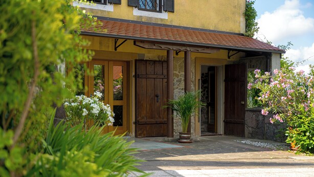 Un bâtiment doté d’une façade en pierre, de portes en bois et d’un toit recouvert de tuiles.