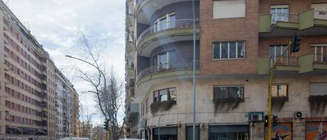 A multi-story building with balconies, a pedestrian crossing, and a traffic light.