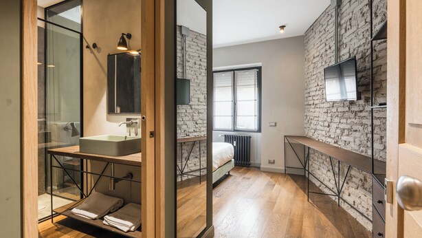 A modern bathroom with a glass shower enclosure, a large mirror, and a wooden vanity. - Licia (Rome)