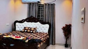 A bedroom with a large bed, a ceiling fan, recessed lighting, and an air conditioning unit.