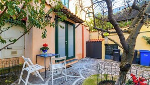 A courtyard with a tiled floor, a white chair, a table, and a potted plant.